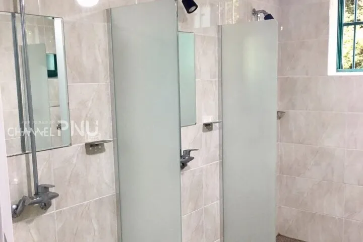 Shared shower room with curtained stalls in the older dorm building